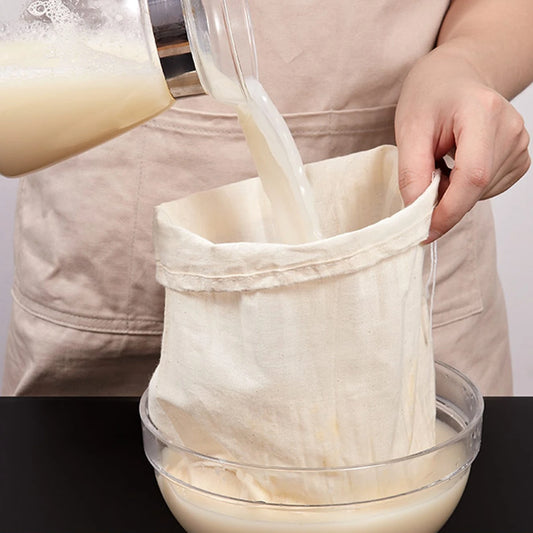 Organic cheesecloth filtering silky smooth nut milk, highlighting its tight weave and natural, unbleached cotton material. Find it at KitchenHavenCo